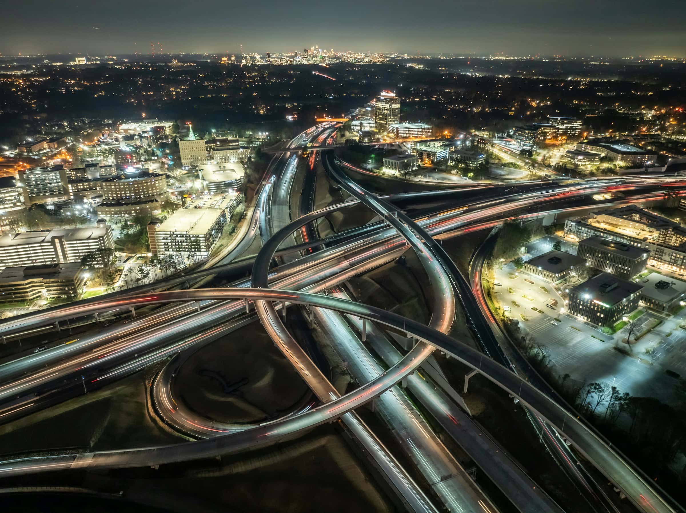 Aerial view of a major highway interchange and city infrastructure at night